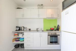 a kitchen with white cabinets and a sink at Kereru Rest in Rotorua