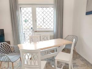 uma mesa de jantar branca e cadeiras com uma janela em Sunnyhome- Ostia Lido vista mare 2 bagni em Lido di Ostia