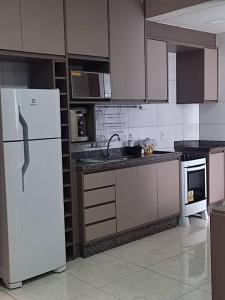 a kitchen with white appliances and a white refrigerator at Apartamento Park 1 in Dourados