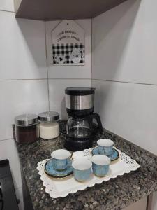 a kitchen counter with four cups and a coffee maker at Apartamento Park 1 in Dourados