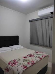 a bedroom with a bed with a flower blanket on it at Apartamento Park 1 in Dourados