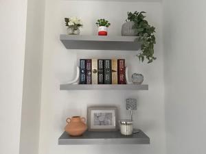 a shelf with books and a picture and a vase at Luxury Apartment with Balcony in Dewsbury