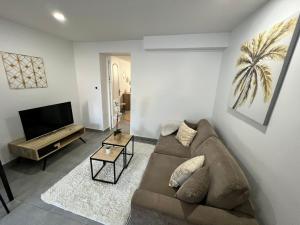 ein Wohnzimmer mit einem Sofa und einem Flachbild-TV in der Unterkunft Appartement en rez-de-jardin in Vitry-sur-Seine