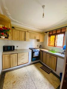 una cucina con mobili in legno e un forno a piano cottura di A Fineshade Apartment a Jinja