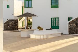 a white building with a table and a umbrella at Casa Narnia in Puerto del Carmen