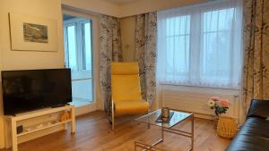 ein Wohnzimmer mit einem gelben Stuhl und einem TV in der Unterkunft Renovierte 4.5Zimmerwohnung 90m2 in Wil