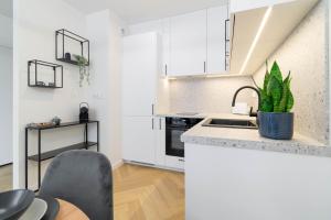 een keuken met witte kasten en een wastafel en een plant bij Blue Apartment Ceglana - FREE PARKING - Self check-in in Katowice