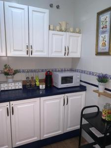 a kitchen with white cabinets and a microwave at Apartamento Cool Garden con Terraza privada A 5 min del metro in Mairena del Aljarafe