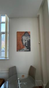 a painting of a man on a wall next to a table at Stunning Salford Quays Apartment in Manchester
