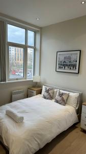 a bedroom with a large white bed with a window at Stunning Salford Quays Apartment in Manchester