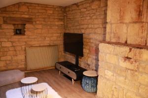 - un salon avec un mur en briques et une télévision dans l'établissement La Petite Maison de Torgny, à Torgny