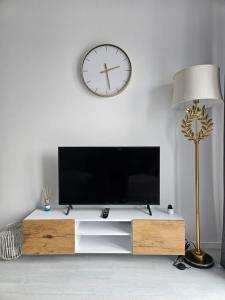sala de estar con TV y reloj en la pared en Apartament - Osiedle Przylesie, en Namysłów