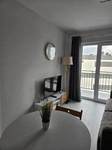 een witte woonkamer met een tafel en een televisie bij Apartament - Osiedle Przylesie in Namysłów