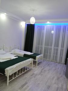 2 camas en una habitación con cortinas moradas en Geno Guest House en Kvariati