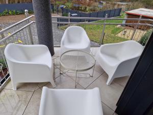 3 weiße Stühle und ein Tisch auf dem Balkon in der Unterkunft The Ferienwohnung in Bremen