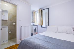 a white bedroom with a bed and a washing machine at Streatley Apartments in London
