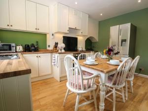 a kitchen with a wooden table and white chairs at Charming Country Cottage in Selborne