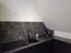 a kitchen with a sink and a black counter top at Chalet Coté Cour à 10 min de la Station in Oz
