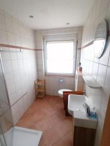 łazienka z umywalką, toaletą i oknem w obiekcie Ferienwohnung Waldblick w mieście Bad Essen