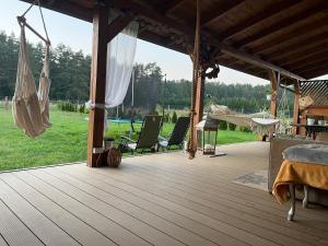 a wooden deck with two chairs and a hammock at Willa na Mazurach Ametyst in Szczytno