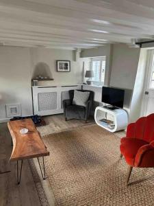 昂德尔Grade II listed Cottage in Oundle with private courtyard的客厅配有沙发椅和电视
