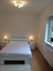 ein Schlafzimmer mit einem weißen Bett und zwei Nachttischen in der Unterkunft Alter Ortskern Worpswede in Worpswede