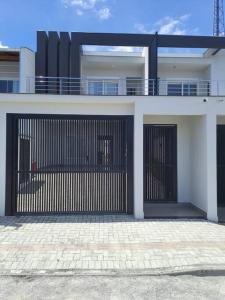 una casa con una puerta negra delante de ella en Sobrado com piscina, banheira e garagem coberta. en Piçarras