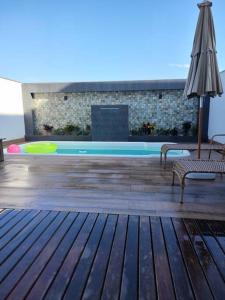 une piscine avec deux bancs, un parasol et un frisbee dans l'établissement Sobrado com piscina, banheira e garagem coberta., à Balneário Piçarras