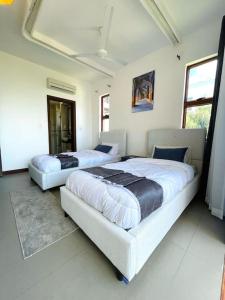 two beds in a white room with two bedsskirts at Stunning 2 Bed Room Unit with Ocean View in Mariakani
