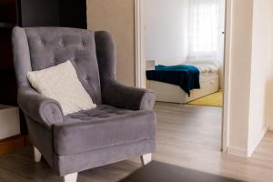 einen grauen Stuhl mit Kissen im Wohnzimmer in der Unterkunft 5 min Apartment in Banja Luka