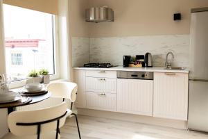 a kitchen with white cabinets and a table at Grand Central Suites in Zandvoort