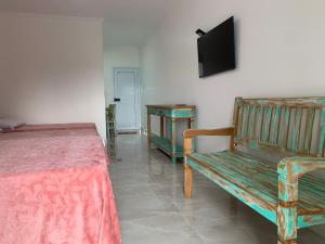 a bedroom with a bed and a bench and a television at São Francisco Flats in Guapé