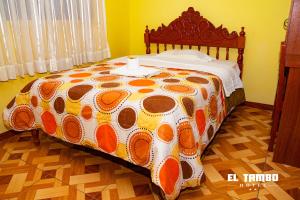 Una cama con un edredón naranja y blanco. en HOTEL EL TAMBO, en Chachapoyas