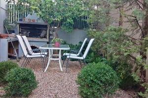 uma mesa e quatro cadeiras num jardim em Pela's studio 6 minutes from the Athens airport em Leondárion