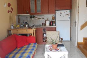 uma cozinha com um sofá vermelho e um frigorífico branco em Pela's studio 6 minutes from the Athens airport em Leondárion