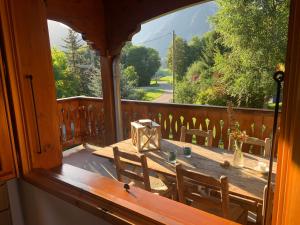 a wooden table and chairs on a porch with a large window at Chalet chez Maurice in Vacheresse