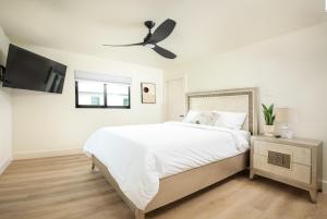 a white bedroom with a bed and a ceiling fan at Black Vanilla - Stylish Symphony 3miles Downtown in Naples
