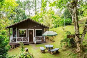 a cabin in the woods with a table and an umbrella at Hospedaje La Naciente in Turrialba