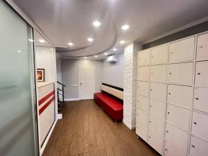 um quarto com um banco vermelho num quarto com armários brancos em Like Hostel em Chisinau