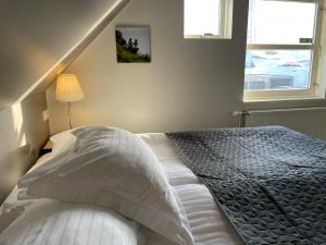 a bedroom with a bed with white sheets and two windows at Akkeri Guesthouse in Stykkishólmur