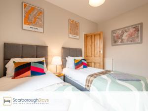 two beds in a small room with two lamps at Mayville Lodge - STUNNING 3 BEDROOMED TOWNHOUSE WITH FREE PARKING in Scarborough