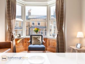 a living room with a chair in front of a window at Mayville Lodge - STUNNING 3 BEDROOMED TOWNHOUSE WITH FREE PARKING in Scarborough