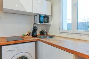 eine Küche mit einer Waschmaschine und einem Waschbecken in der Unterkunft Bel appartement tout équipé de 24m2, proche Paris in Nanterre