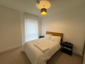 een slaapkamer met een bed met witte lakens en een licht bij Comfort by Mertru in Birmingham