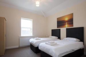 a bedroom with two beds with white sheets at Grosvenor Hotel Rugby in Rugby