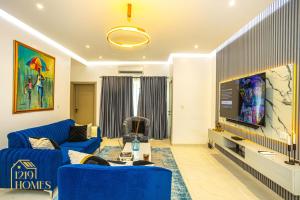 sala de estar con sofá azul y TV en 1219Homes, en Ikeja