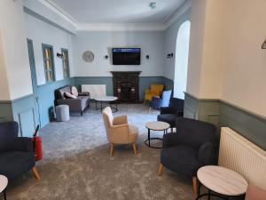a waiting room with couches and chairs and a tv at King's Knoll Hotel in Oban