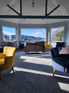 a living room with couches and chairs and windows at King's Knoll Hotel in Oban