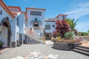 un gran edificio blanco con escaleras y flores en One bedroom house with shared pool terrace and wifi at Canico 1 km away from the beach, en Caniço