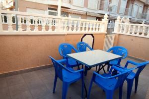 una mesa azul y sillas en el balcón en Adosado con piscina al lado de la playa, en Santa Pola